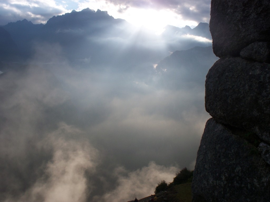 The Watchtower at Machu Picchu This is one of the pictures that I'm most proud of. As all the people were focused on looking out at Wayna Picchu I turned to the right to see the sun breaking through over the mountains. The rocks on the side are part of the watchtower of Machu Picchu which is one of the best places to watch the fog lift from the site itself.